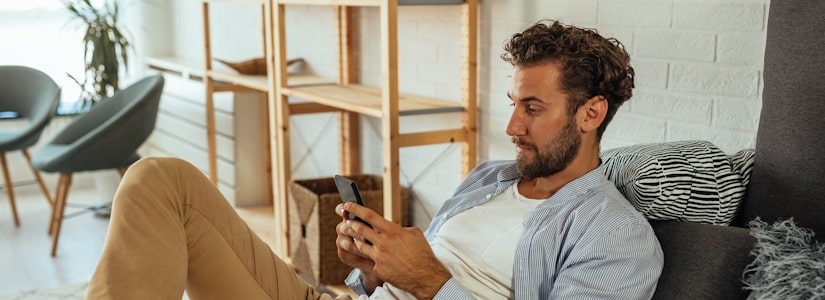 Man on phone checking for affordable credit on sofa